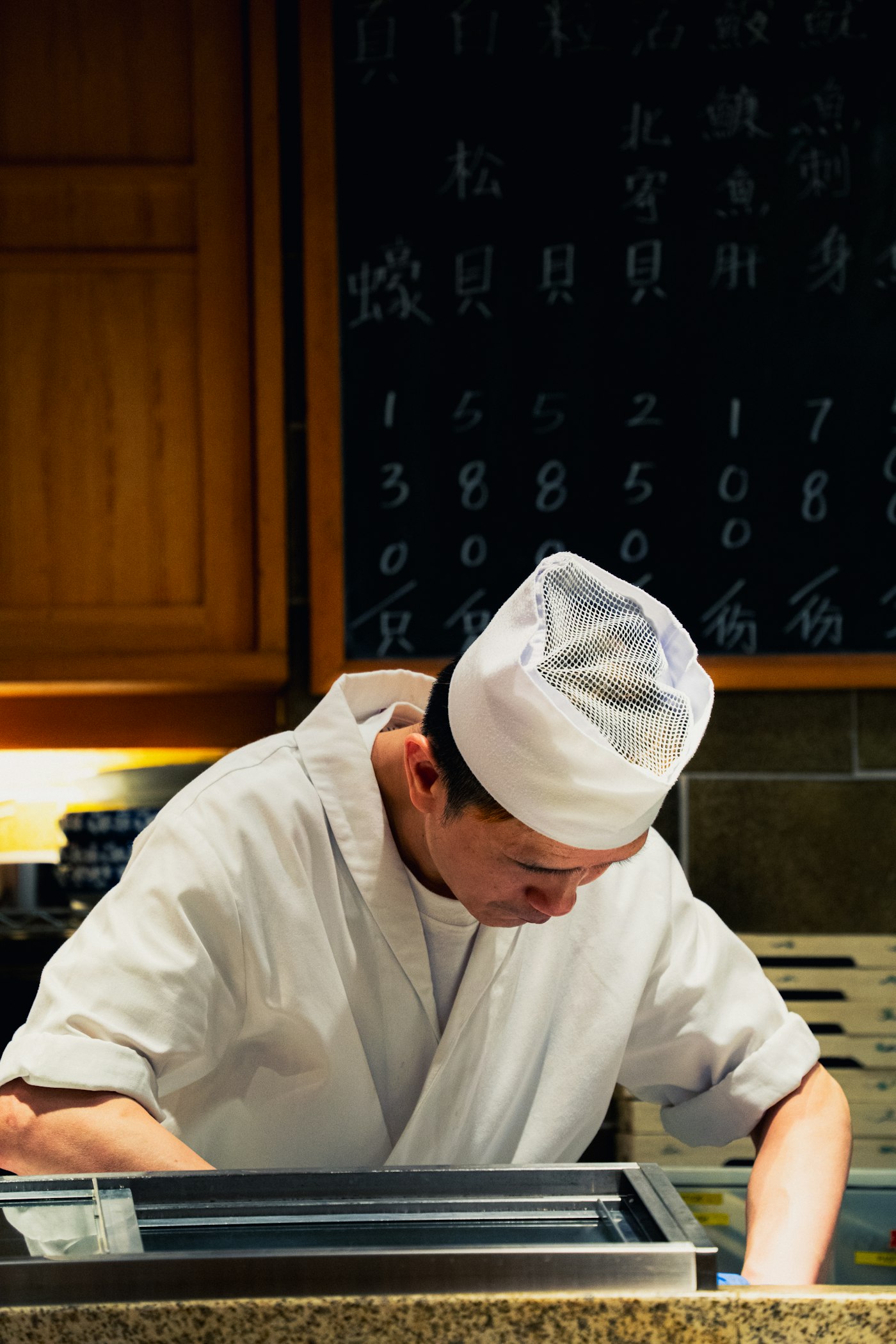 白い調理服で仕込みをする店主