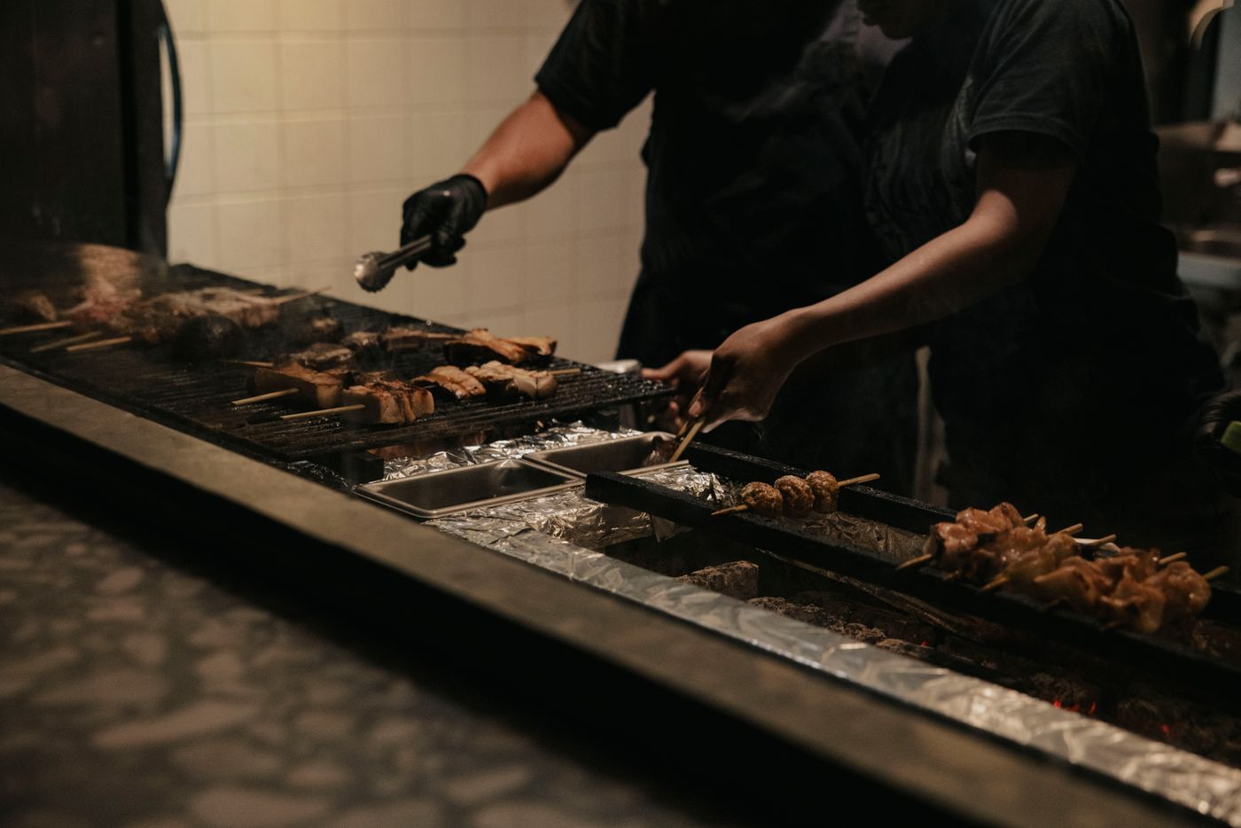 焼き台をはさんで二人が串を返しているところ