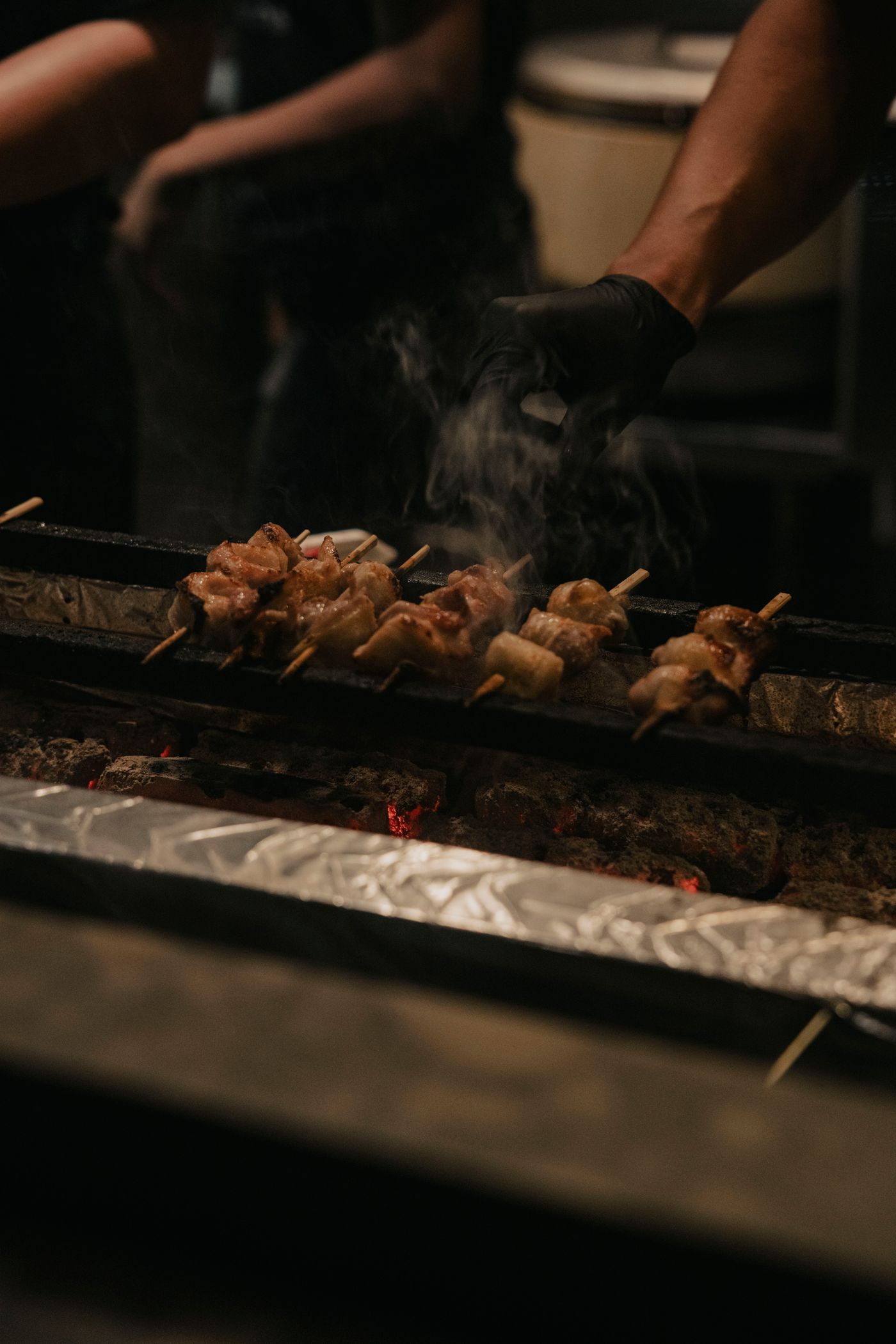 熾った炭の上で串が焼かれ、煙が立ちのぼっているところ