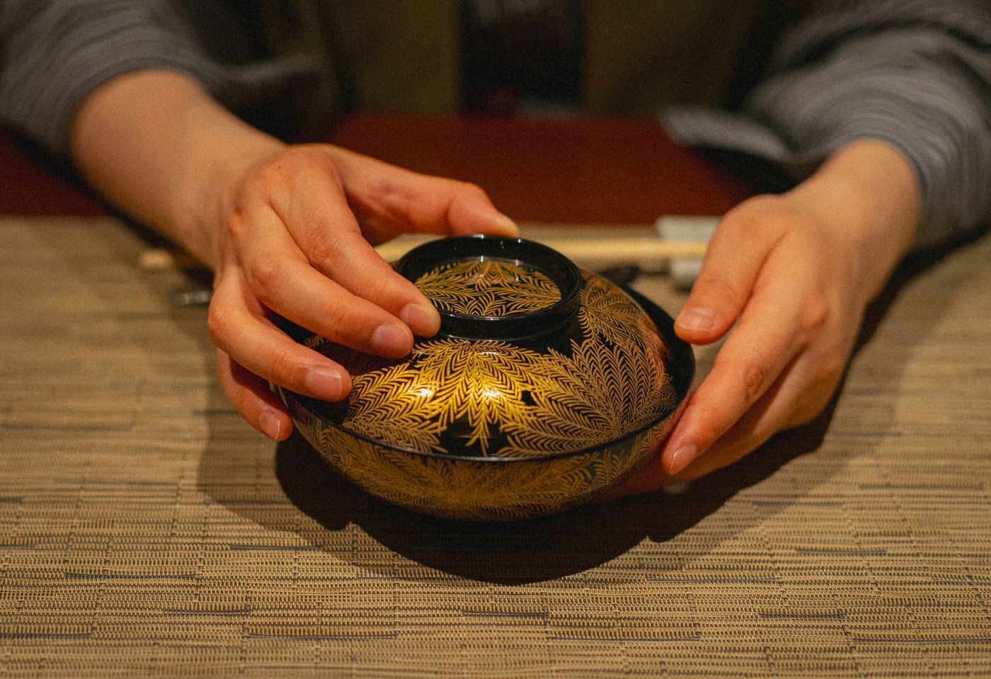 蒔絵の椀を両手で受け取っているところ