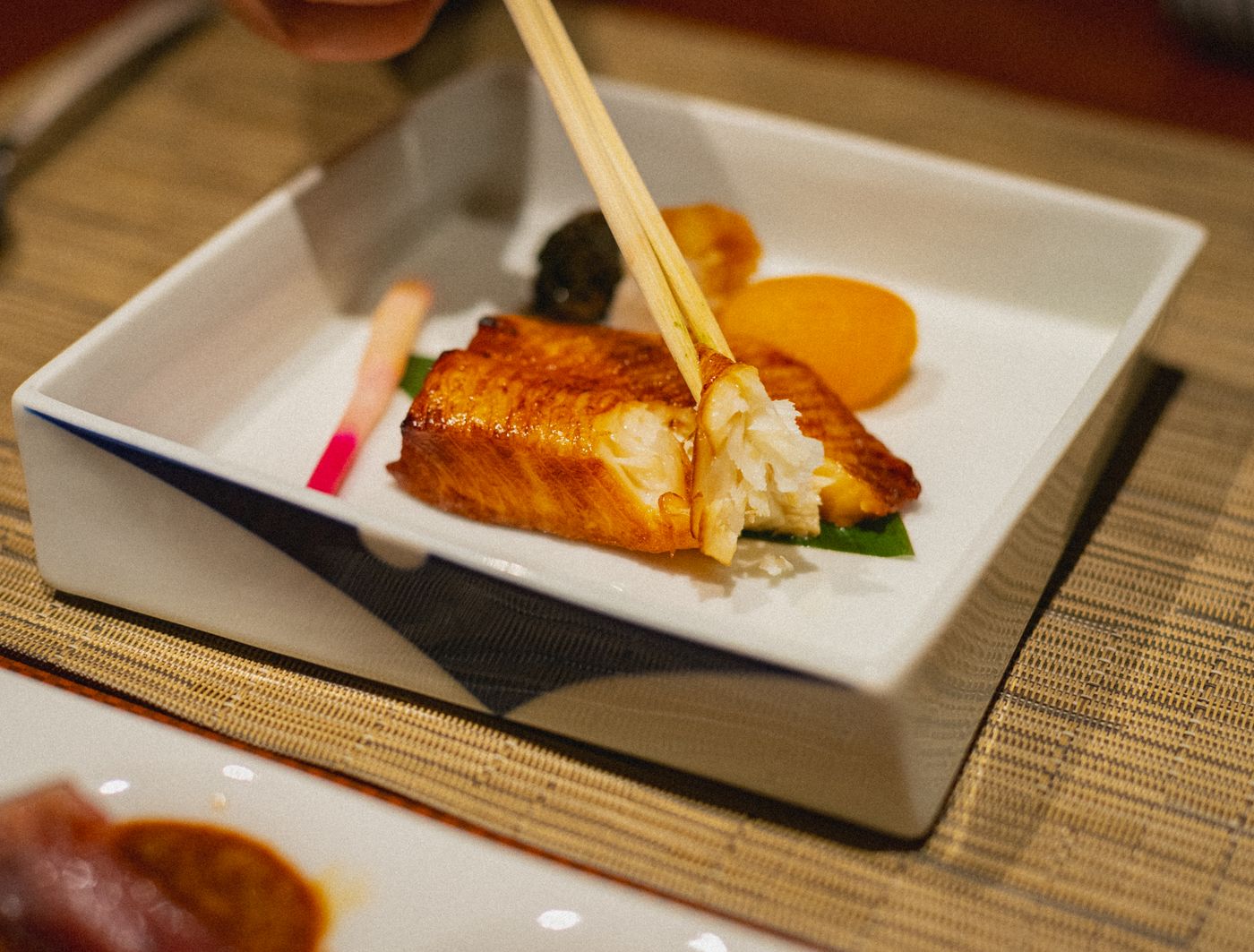 角皿に盛られた焼き魚を、箸でほぐしているところ