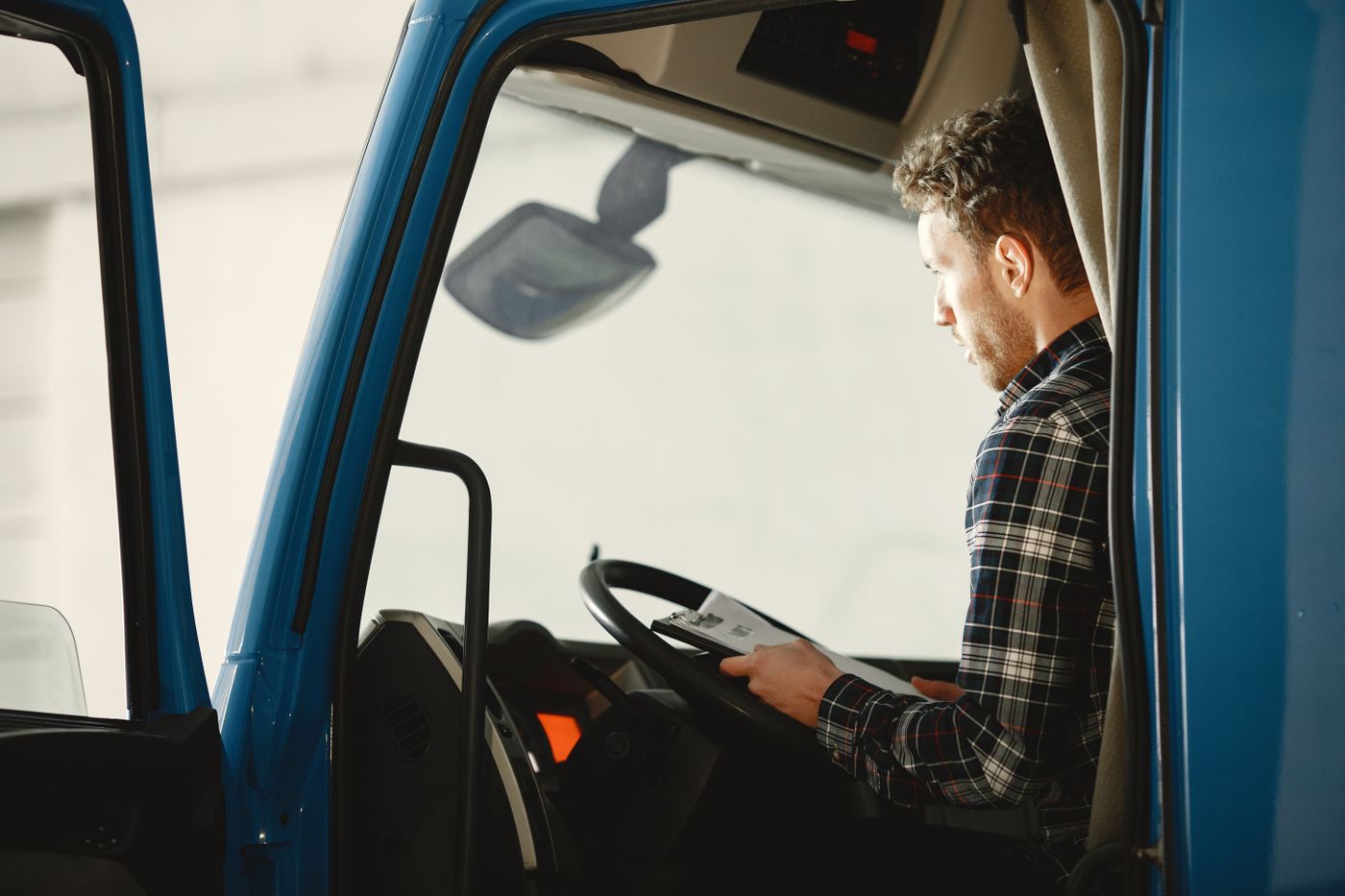 運転席に座った人が、ハンドルの前で書類に目を通しているところ