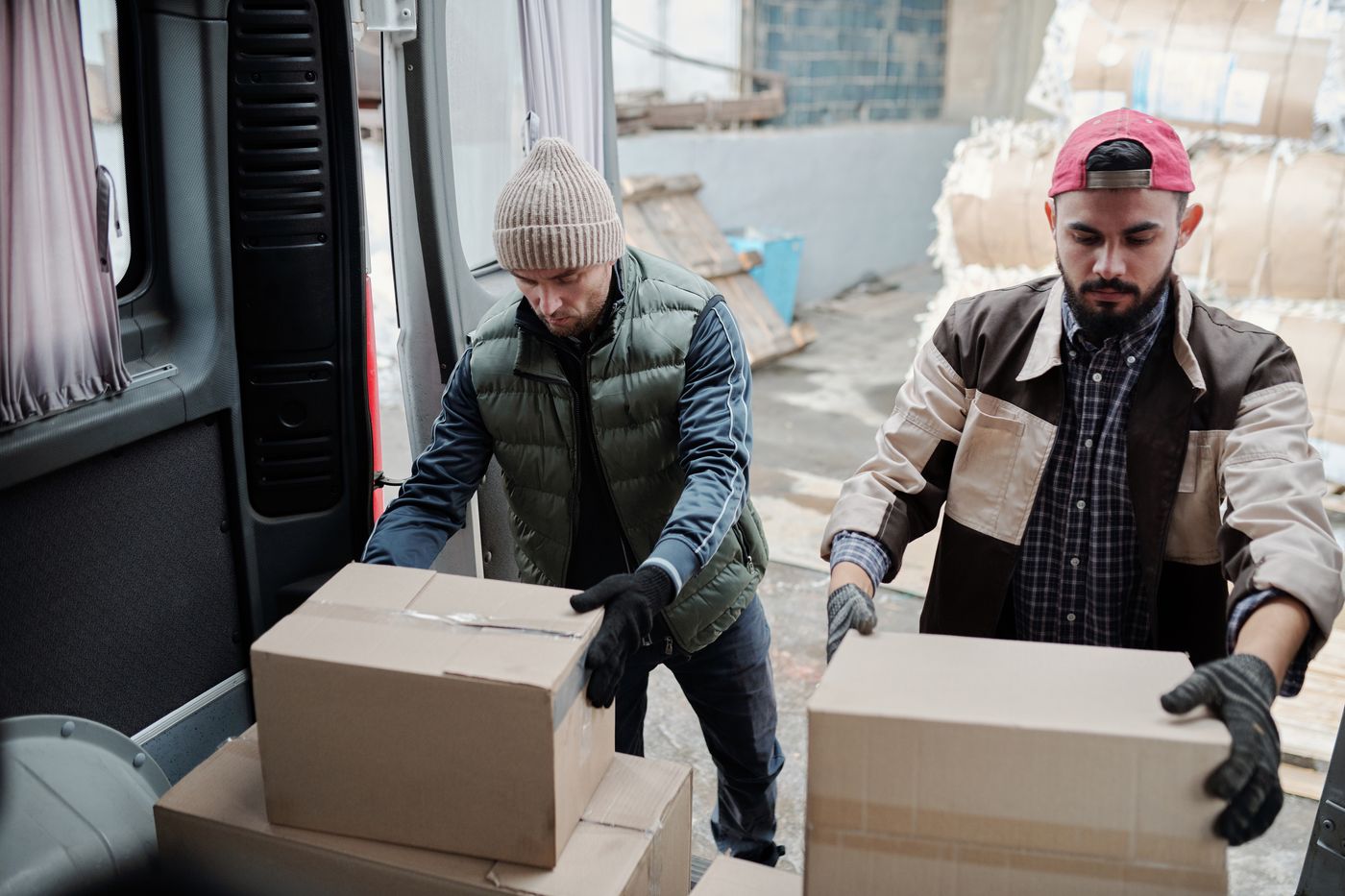 手袋をした二人が段ボール箱をトラックの荷台に積み込んでいるところ